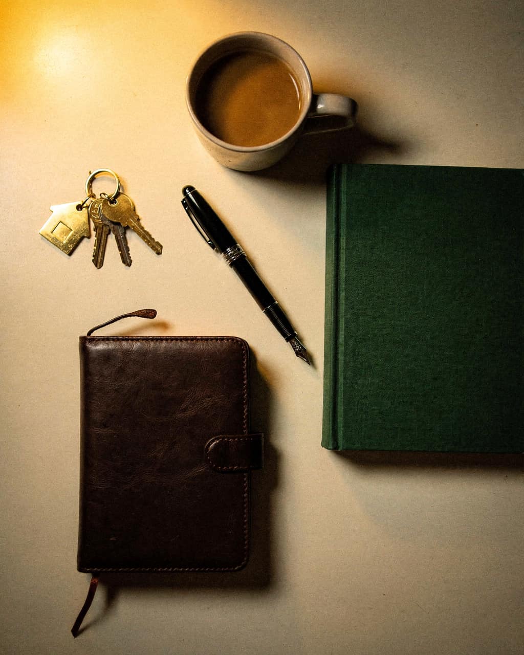 Fountain pen, keys and a leather notebook in warm light — ownership and budget.
