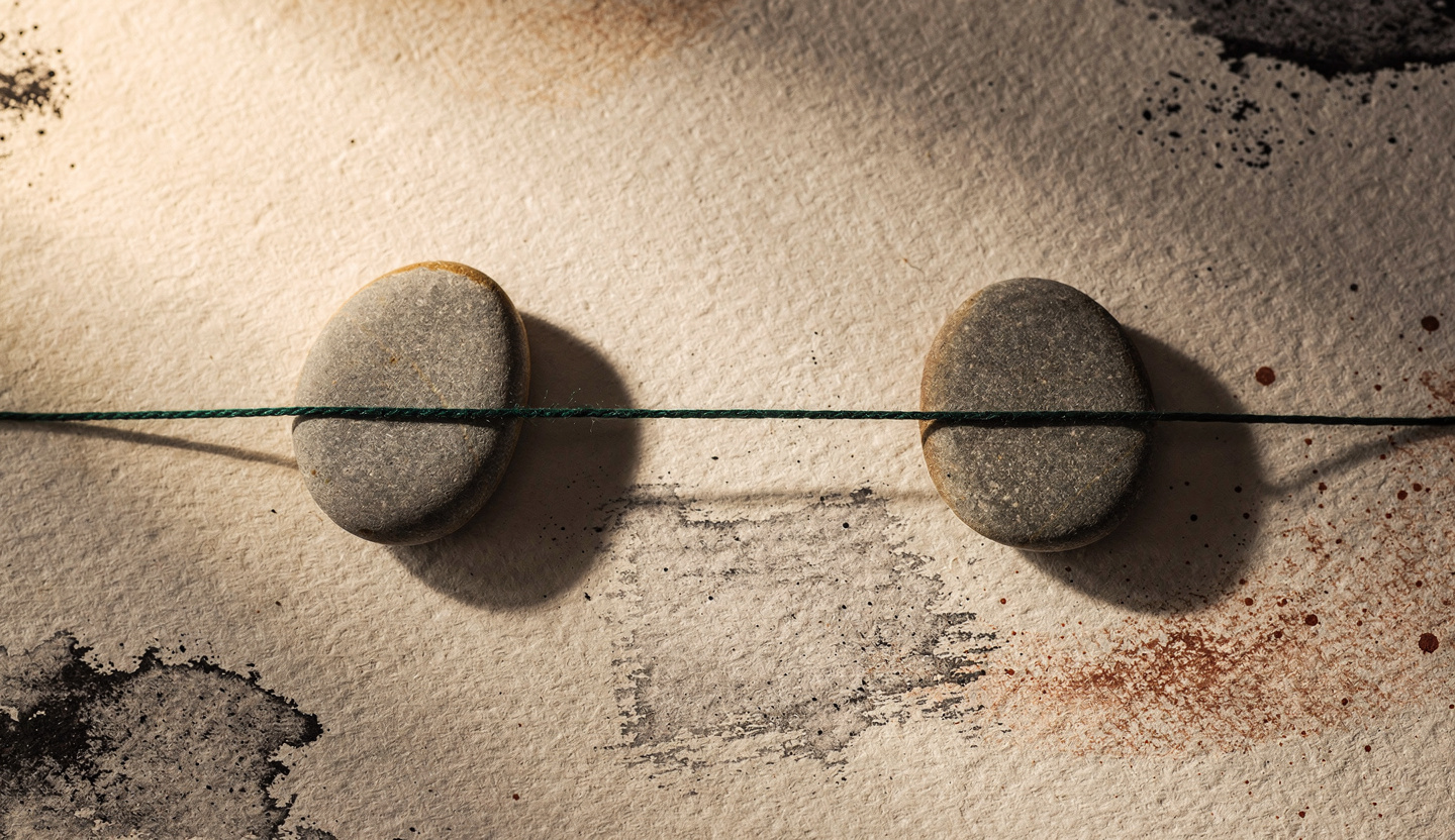 Two river stones joined by a single unbroken forest-green thread forming one continuous bridge, one stone rimmed in amber light: one connected interface, not a relay.